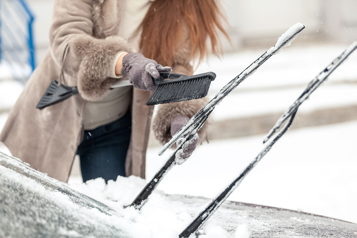 ワイパーに付いた雪を落とす女性